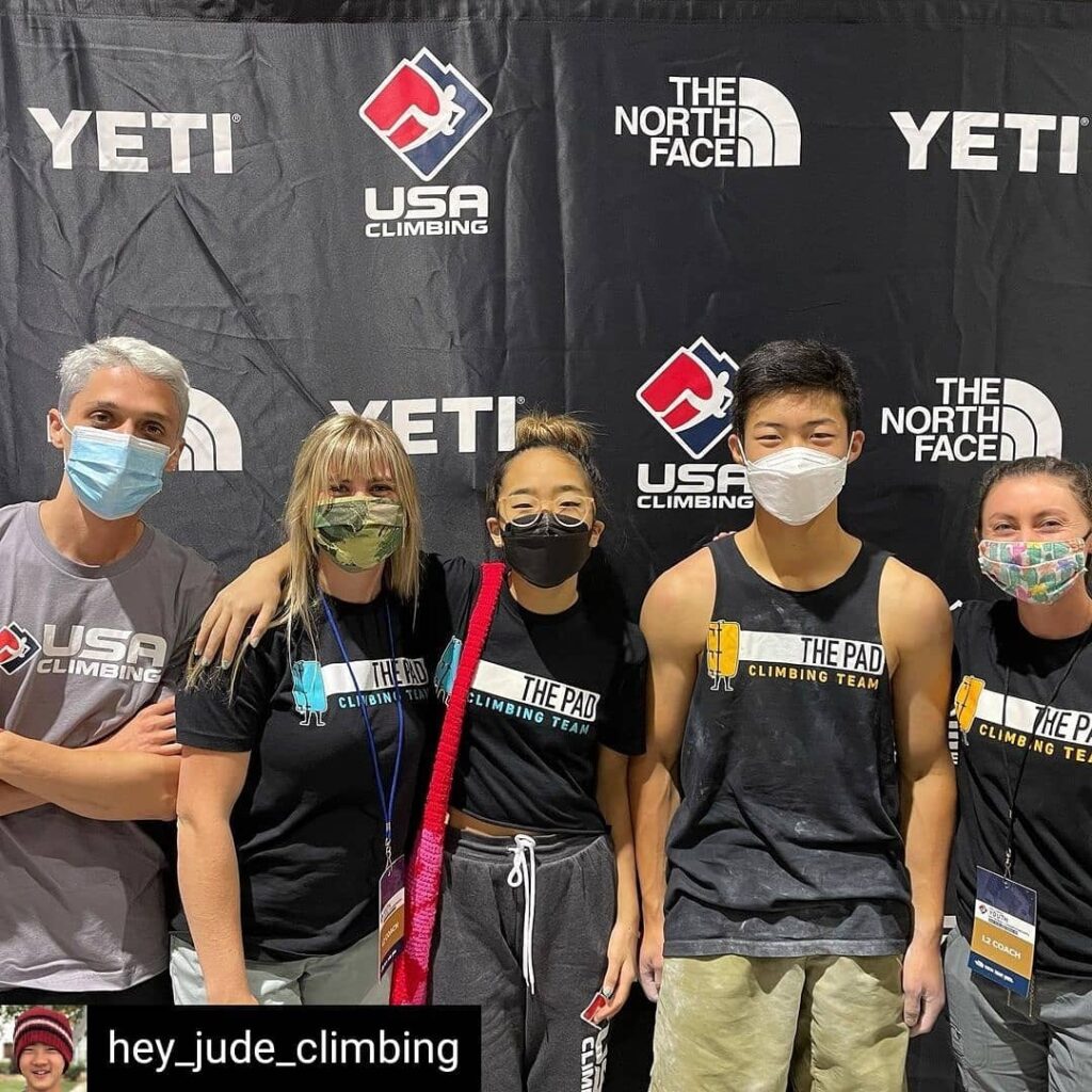 A group of masked people wearing the pad climbing team and USA climbing t shirts and standing behind a large banner