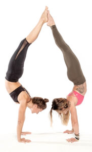 two women perform handstands back to back.