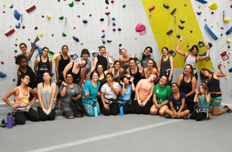 group of women in front of a climbing wall