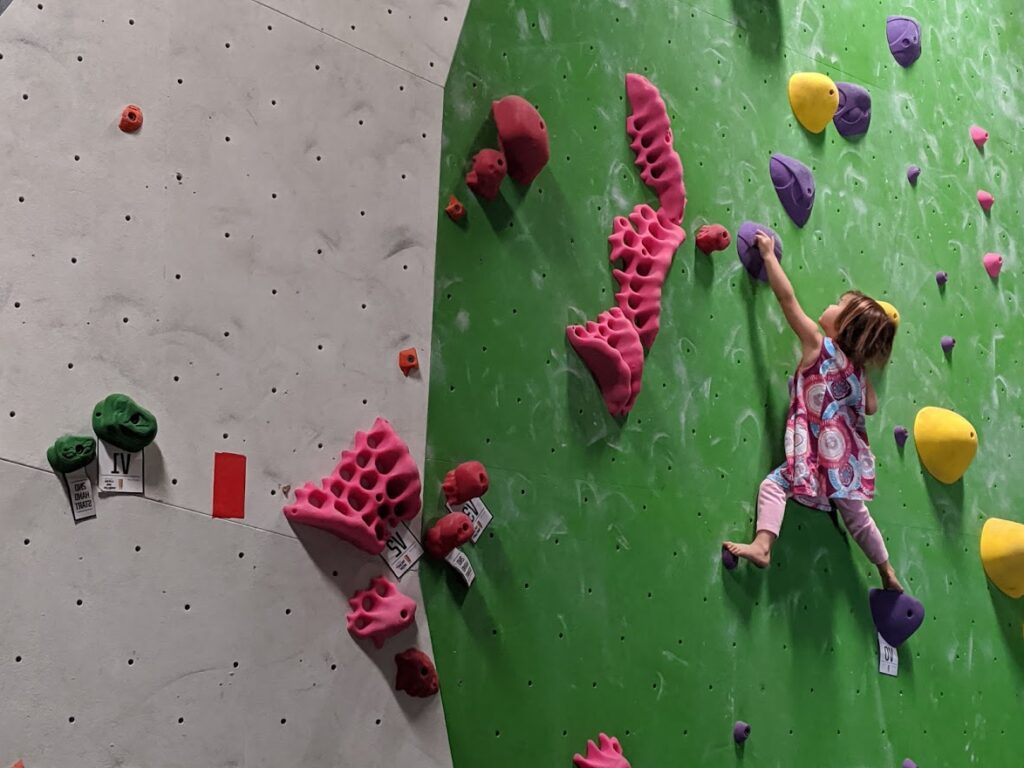 4 year old bouldering on a green wall