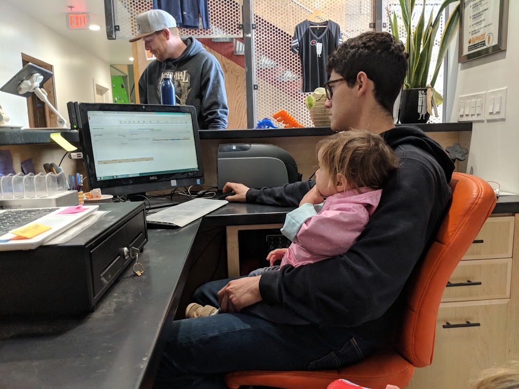 A staff of The Pad Climbing working on a computer at the office while carrying his baby.