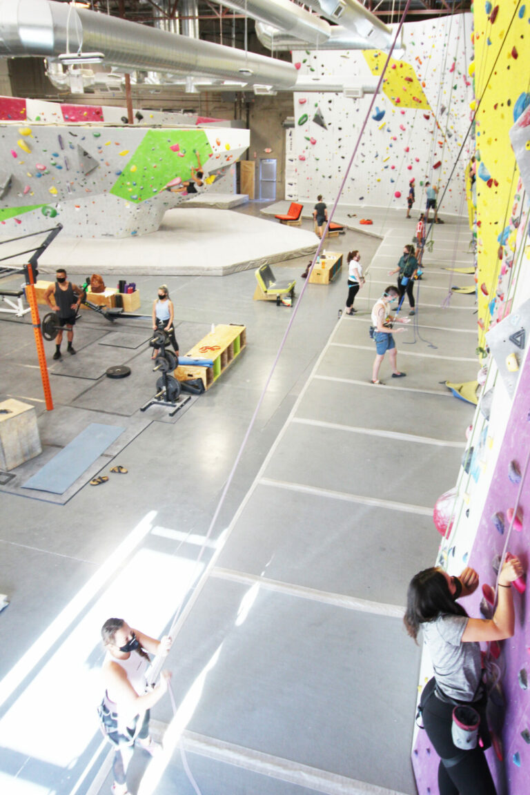 Photo of the Henderson location, people on top rope, some workout equipment, bouldering viewable