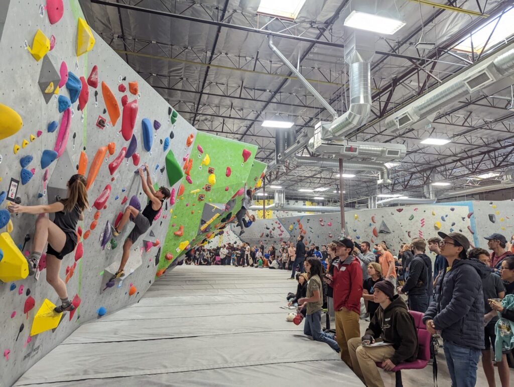 Kids bouldering as crowds look on